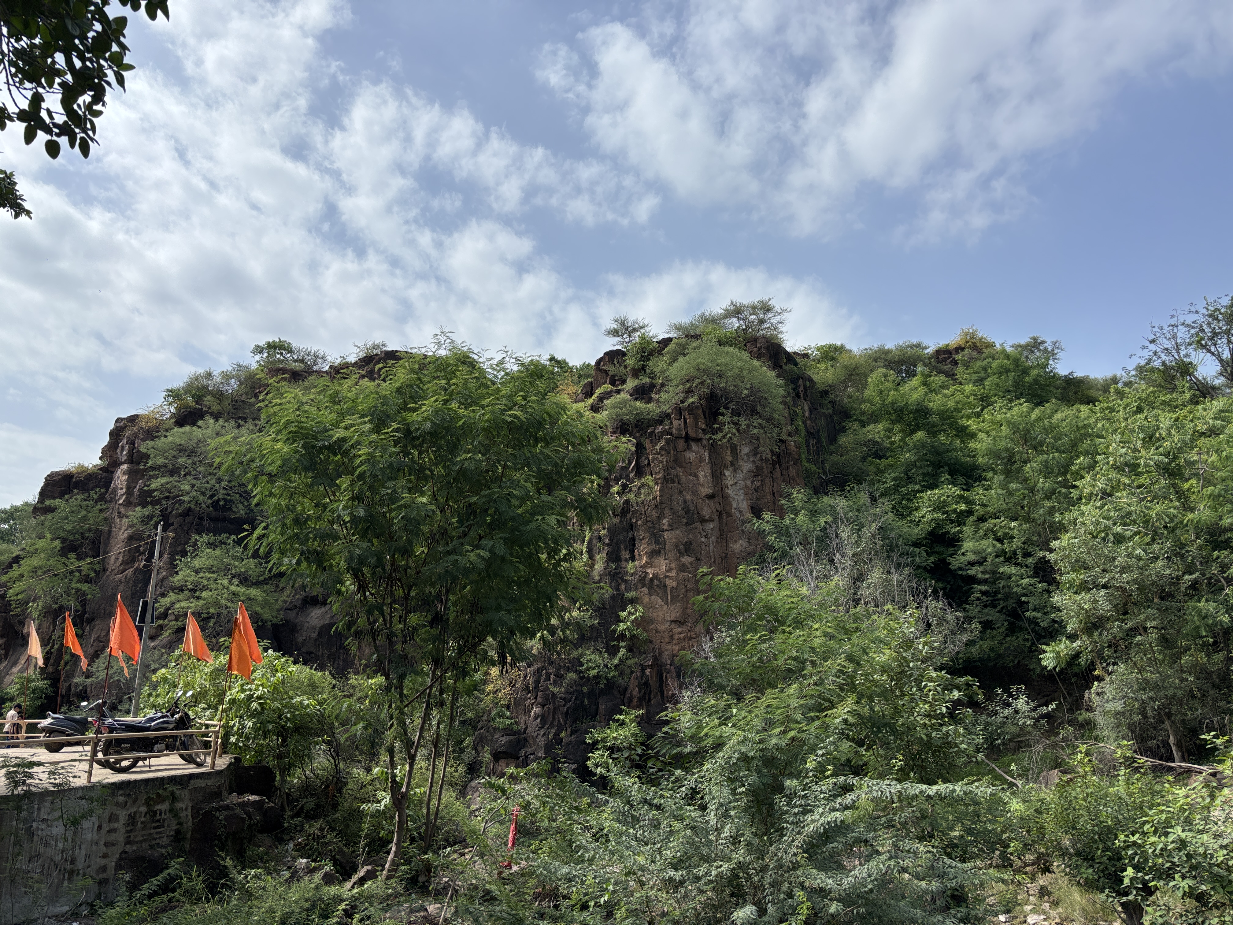Sacred mountain cliffs and saffron flags at Gautameshwar Sihor